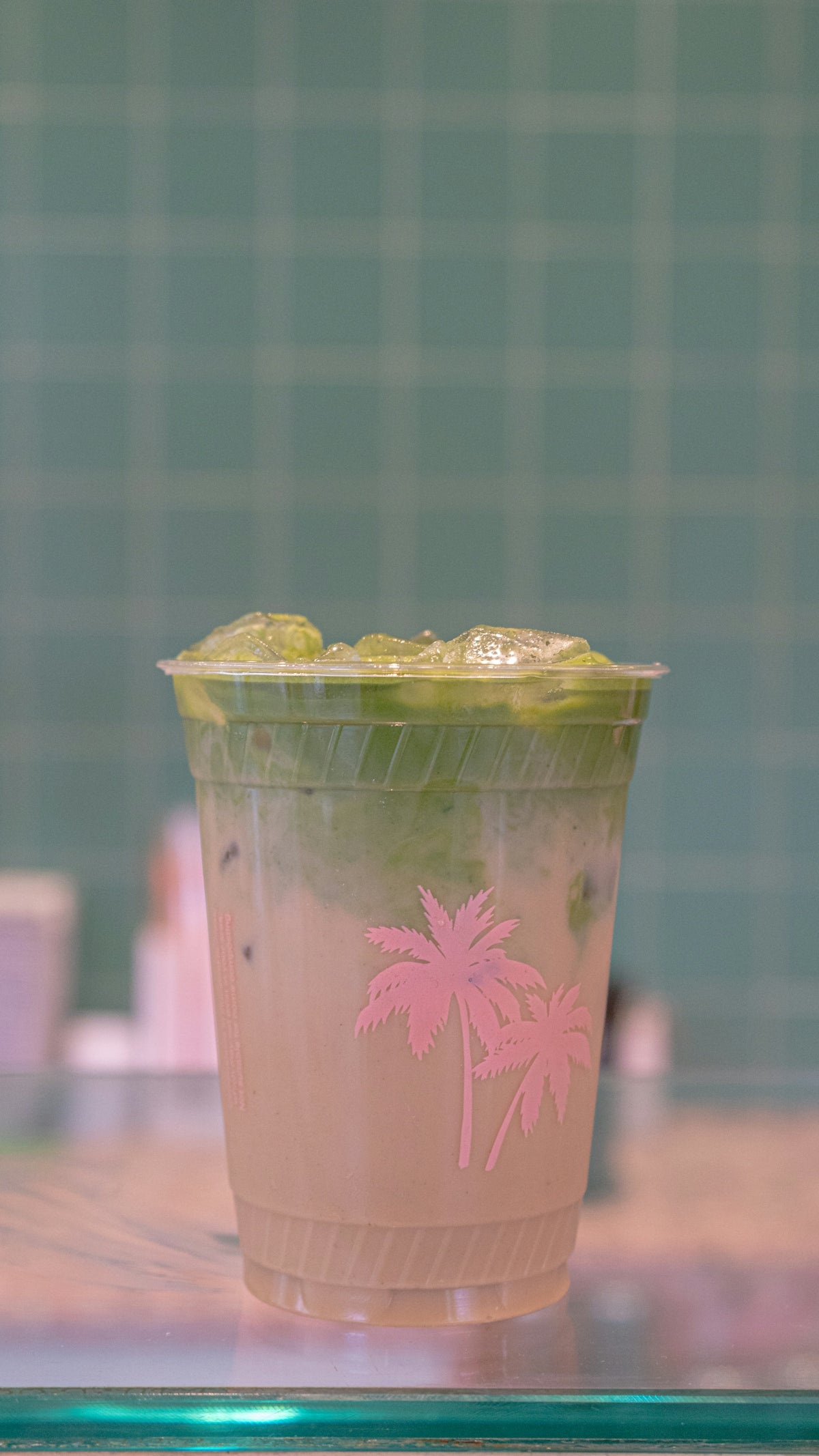 A plastic cup with a pink palm tree on it