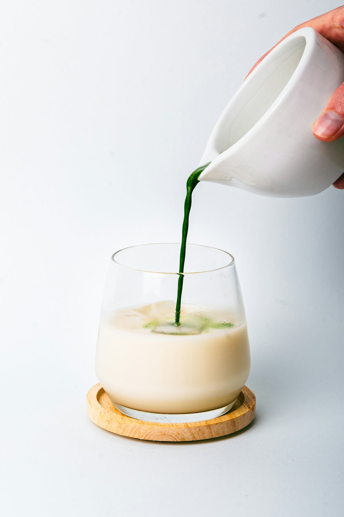 a person pouring a green liquid into a glass