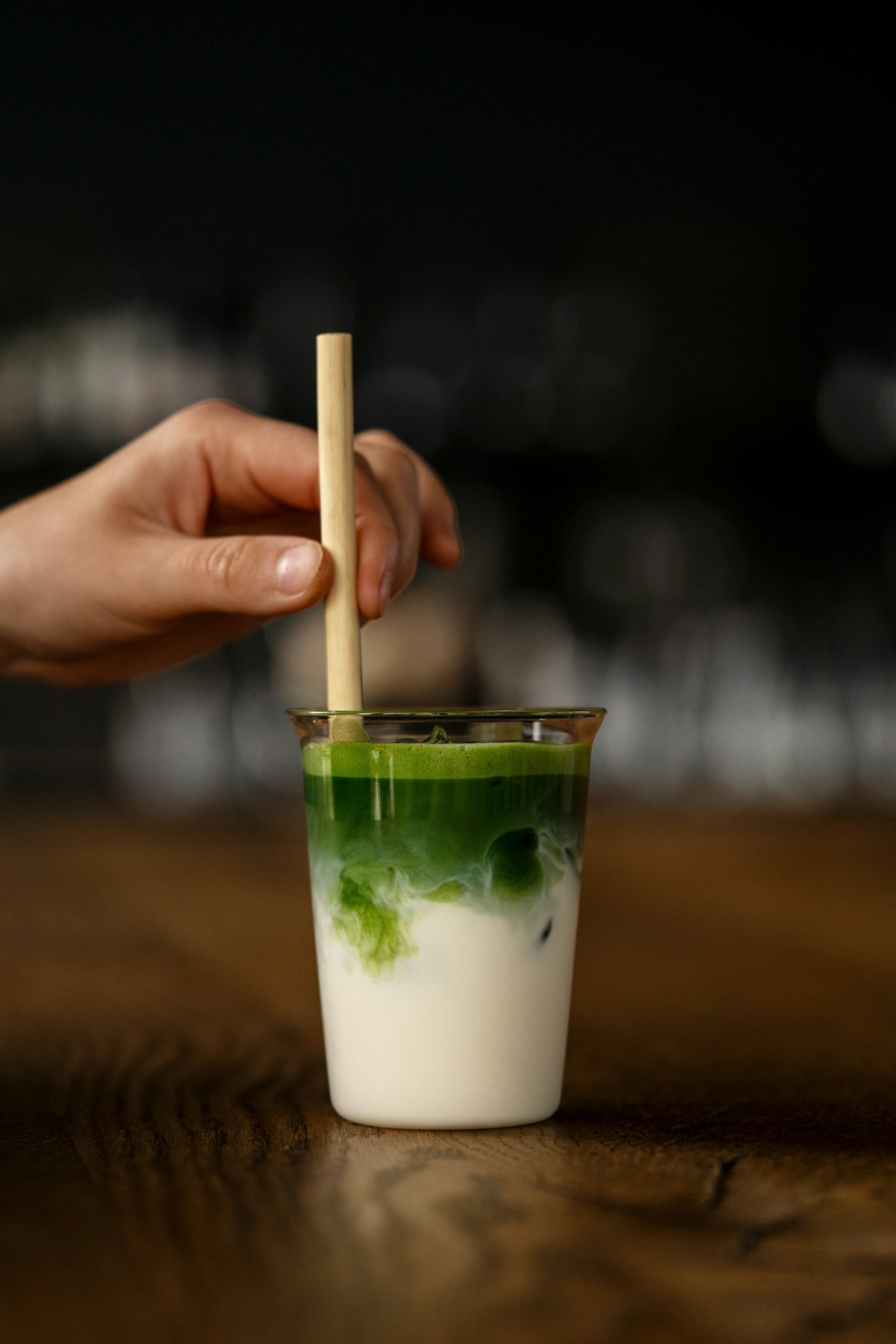a hand holding a wooden stick over a drink