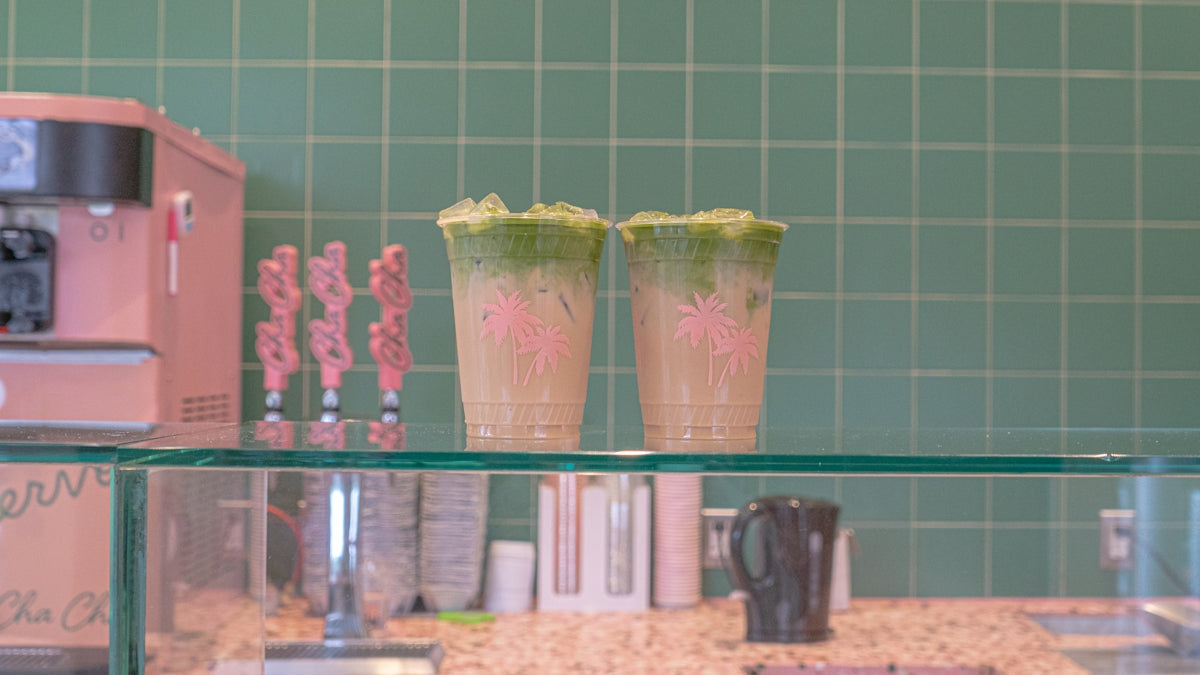 A counter topped with a blender and two cups filled with liquid