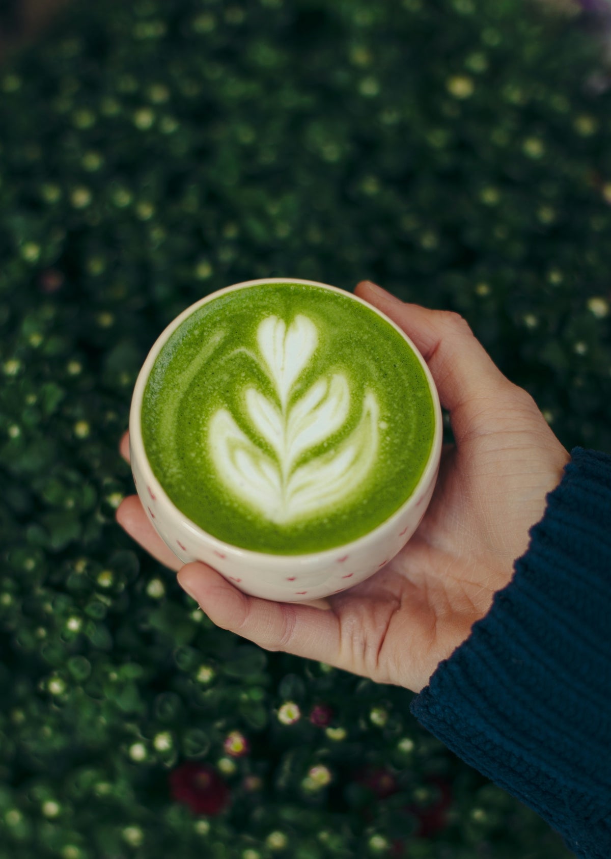 A person holding a cup of green liquid