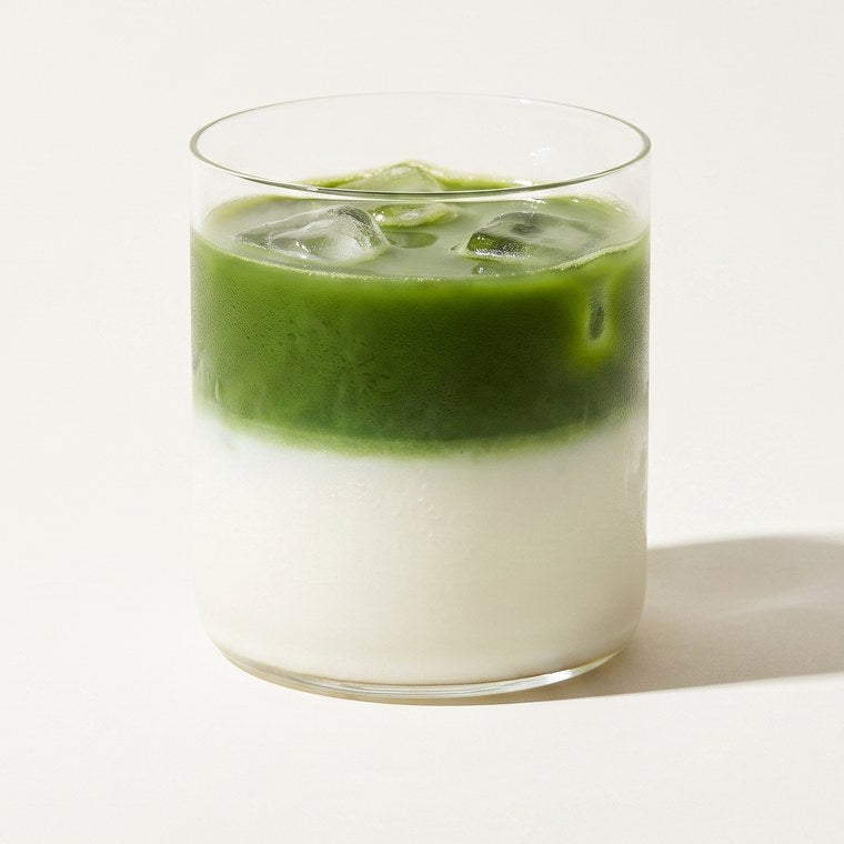 An iced matcha latte in a short glass tumbler