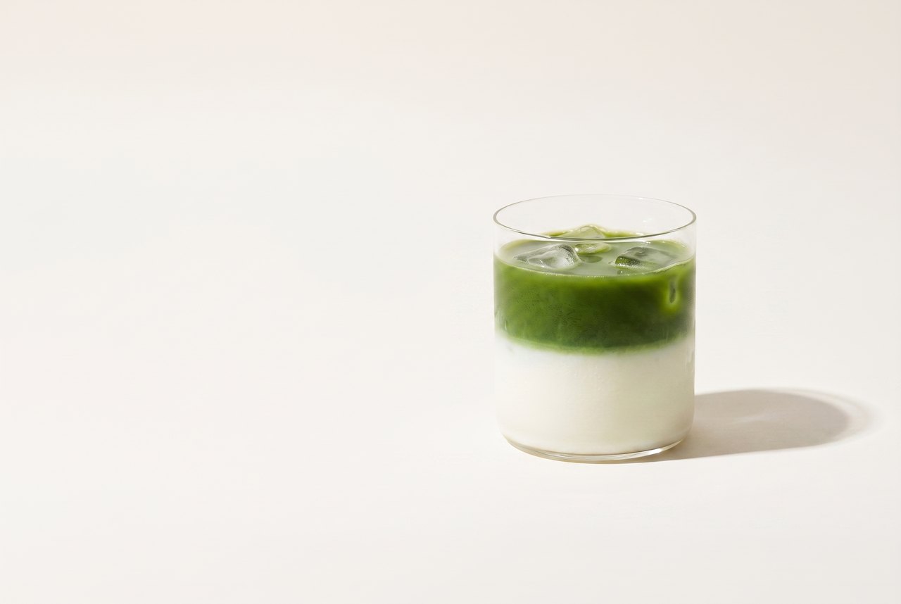 An iced matcha latte in a short glass tumbler